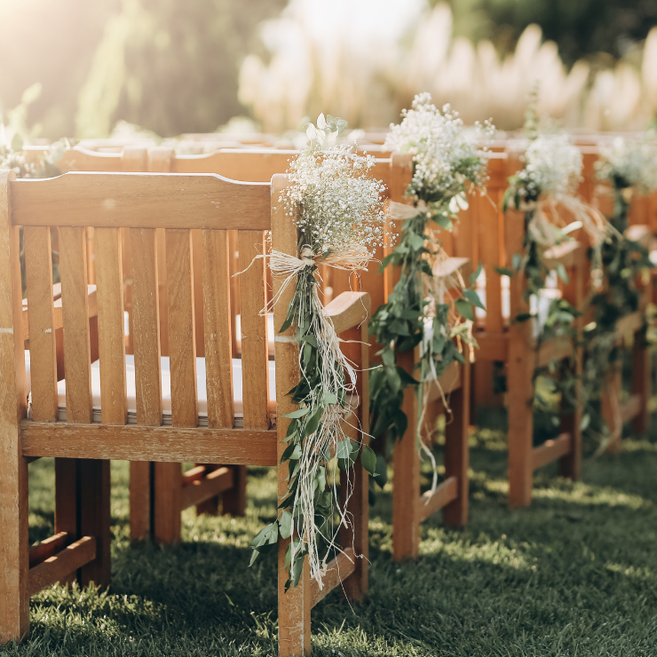 Sage green wedding ceremony wooden chairs with green foliage decorations.