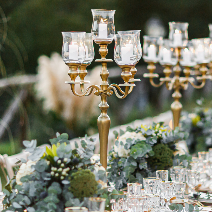 Sage green wedding reception table setting with gold candelabras and eucalyptus foliage centerpieces.