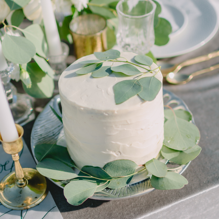 Sage green wedding cake with white cream decorated with eucalyptus leaves.