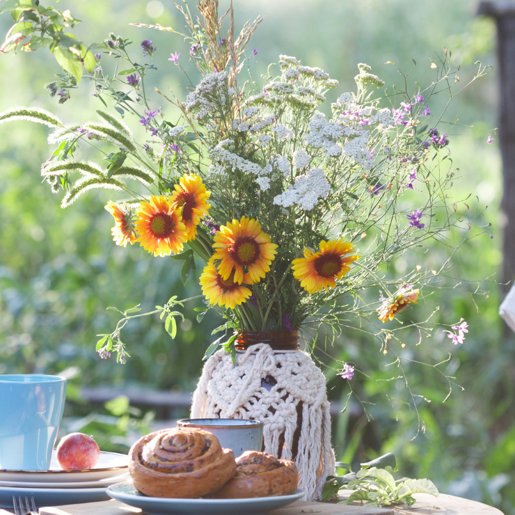 Bride to bee bridal shower table decor with a boho crochet vase with wildflowers and honey swirl pastries.