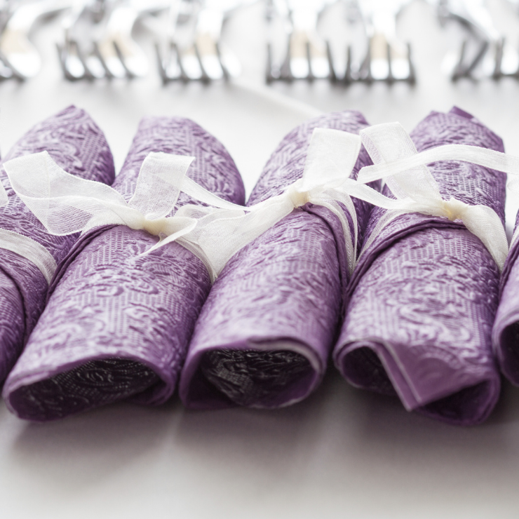 Dusty mauve wedding napkins rolled up and tied with white organza ribbon.