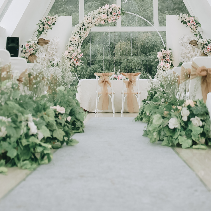 Sage green wedding arbor with flowers and twinkle lights.