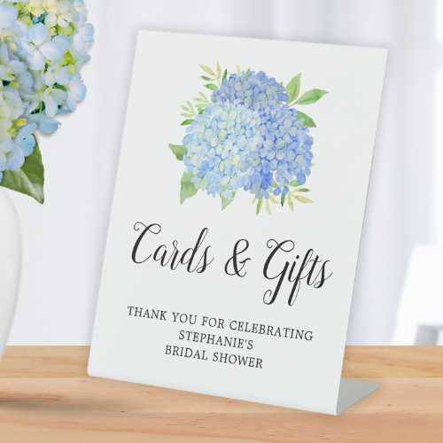 Blue hydrangea bridal shower cards and gifts pedestal sign with modern watercolor blue hydrangea bouquet with foliage and script typography.