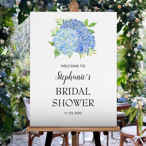 Blue hydrangea bridal shower welcome foam board on easel with modern watercolor blue hydrangea bouquet with foliage and script typography.