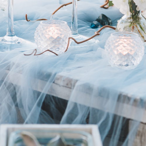 white glass tea light candles with soft blue tulle on table setting