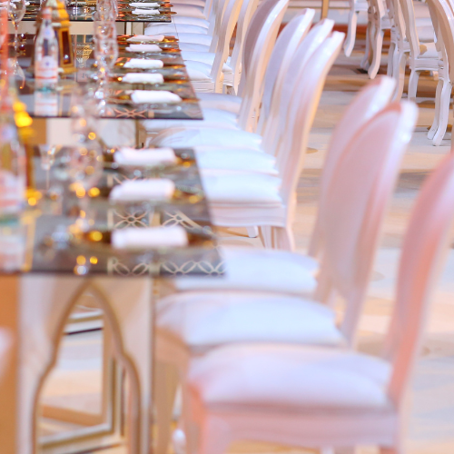 Coquette bridal shower theme inspiration image of dinning table setting with pink chairs and vintage style themed table.