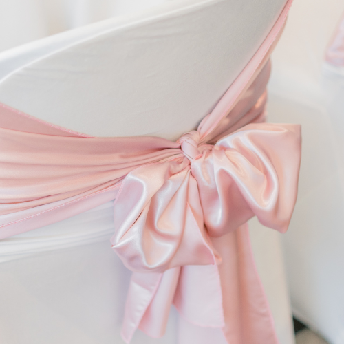 Coquette bridal shower theme inspiration image of a blush pink silky bow chair sash.