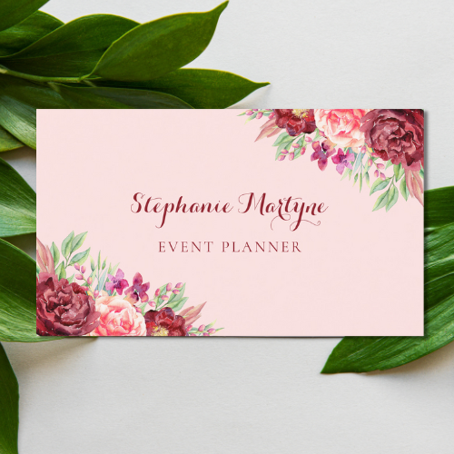 Botanical inspired event planner business card with watercolor burgundy and blush roses with foliage. Text is in a modern script typography font on a blush pink background.