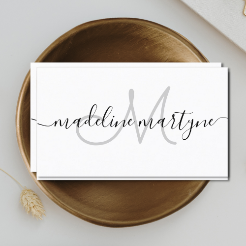 Elegant white business cards with modern script typography font monogram logo in white on a black background.