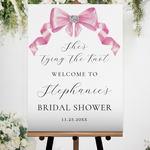 Shes tying the knot bridal shower coquette themed acrylic welcome sign featuring a chic glam silky pink bow with sparkling rhinestones design and customizable modern script typography.