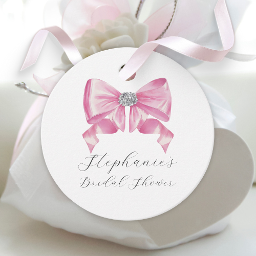 Shes tying the knot bridal shower coquette themed round favor tag featuring a chic glam silky pink bow with sparkling rhinestones design and customizable modern script typography.