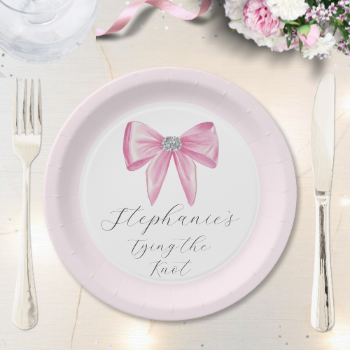 Shes tying the knot bridal shower coquette themed paper plate featuring a chic glam silky pink bow with sparkling rhinestones design and customizable modern script typography.